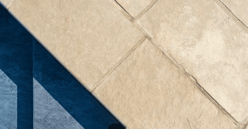 Kota Brown hand-cut limestone pool coping with a textured riven surface beside dark pool water