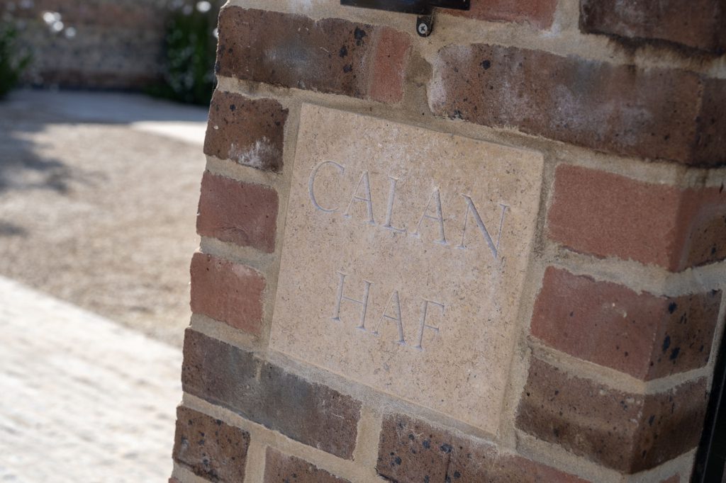 Bespoke limestone house sign carved with Calan Haf, set into a brick gate pier