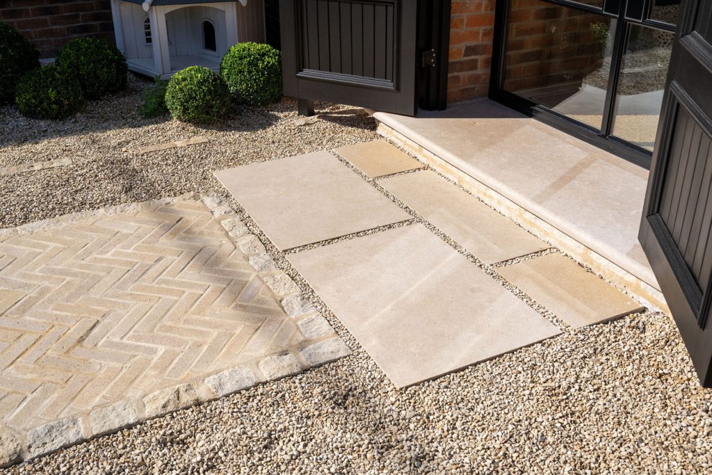 Herringbone Purbeck setts with a pitcher border meeting large La Roche limestone slabs laid with gravel joints at the front door step